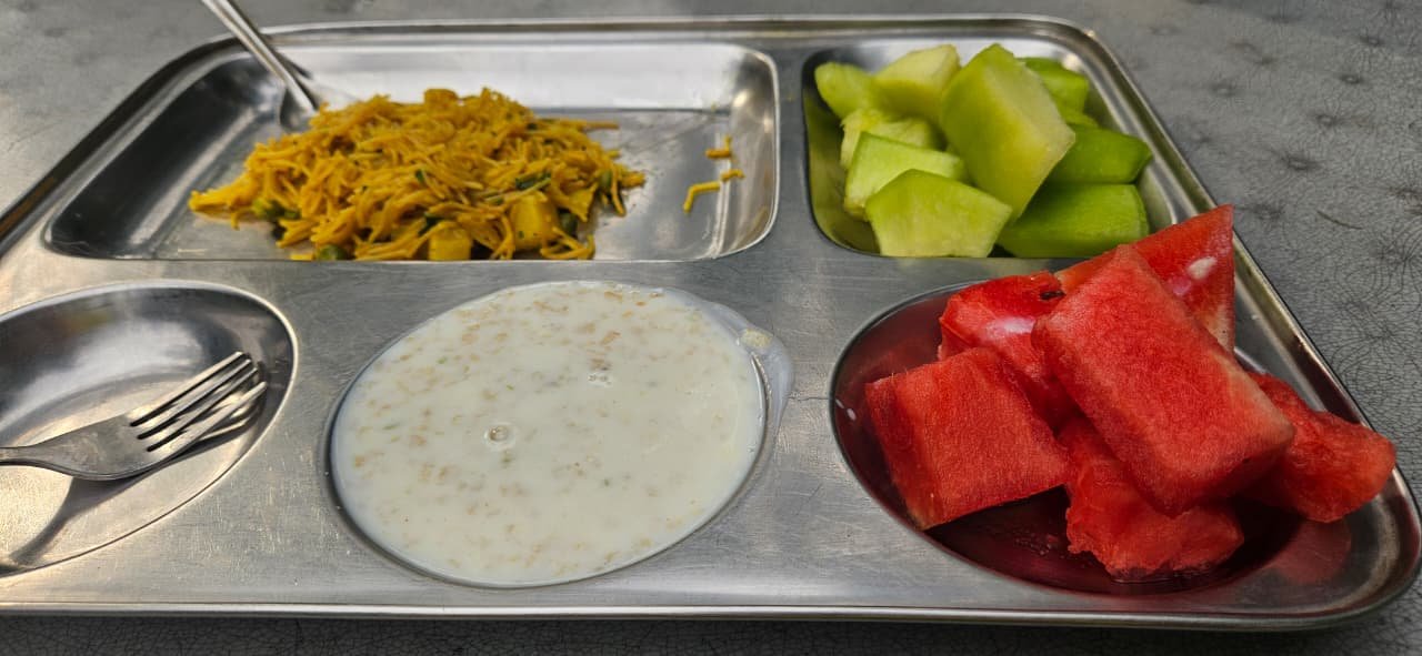 Pure vegetarian thali with veg pulao, fresh fruit, and raita